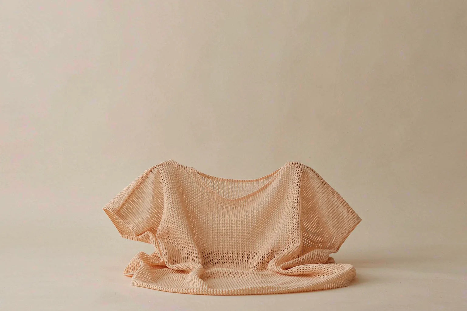 Lightweight fine-gauge neutral knit top in warm apricot tone with open breathable stitch structure, styled for humid tropical weather