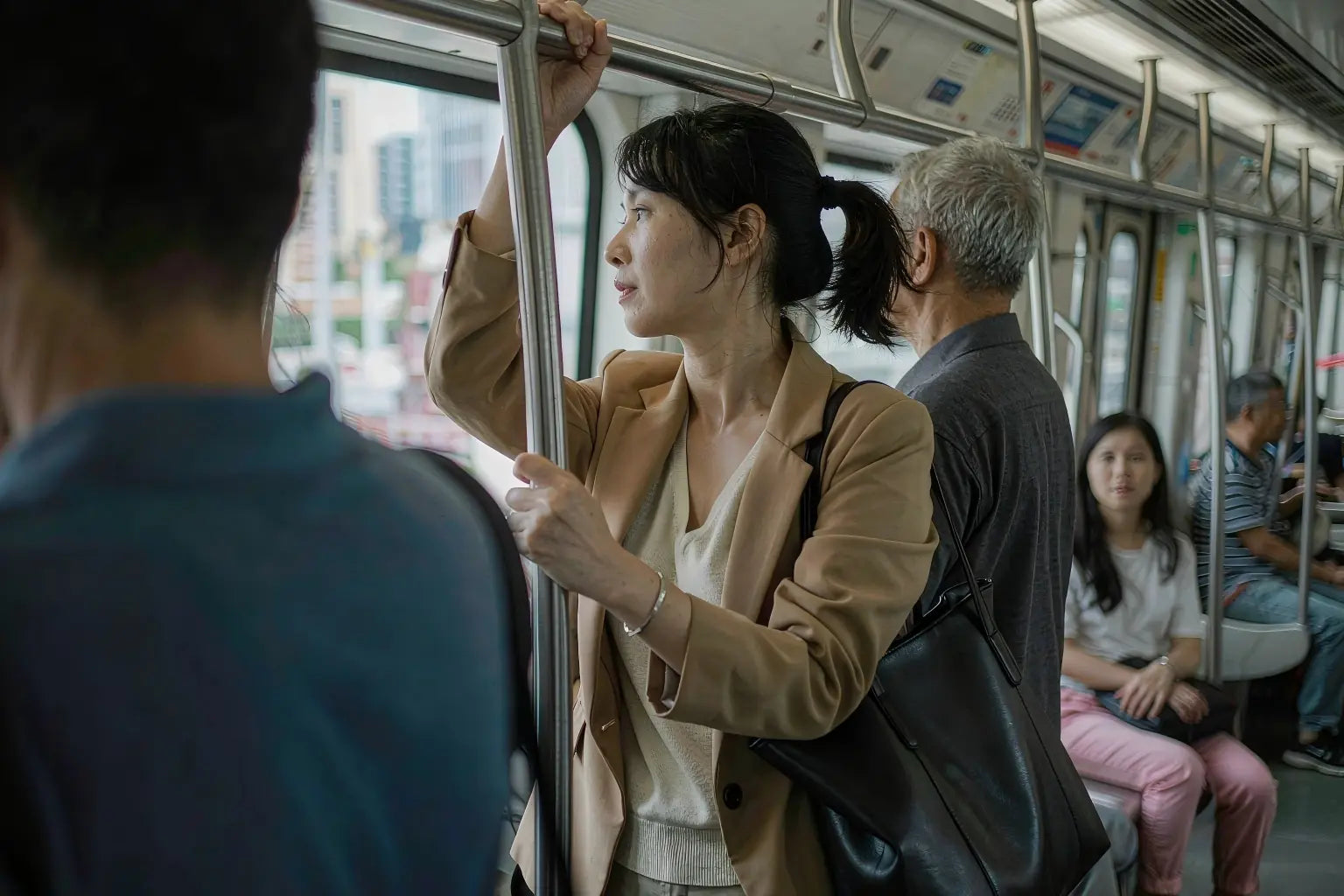 Commuter in a breathable cream knit top inside a morning MRT carriage